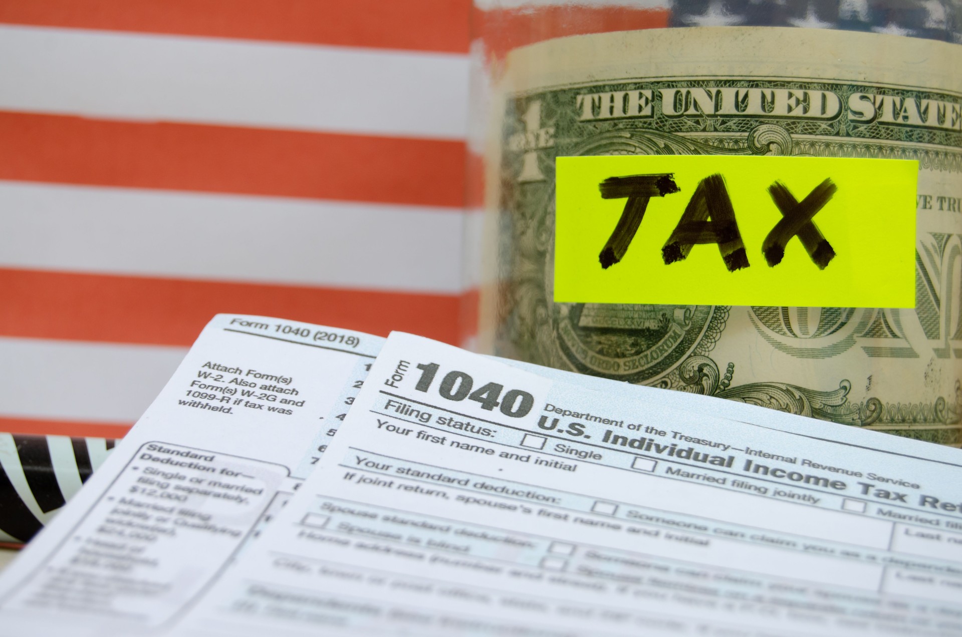 jar with coins and dollar inside with mark tax on it, 1040 form and usa flag