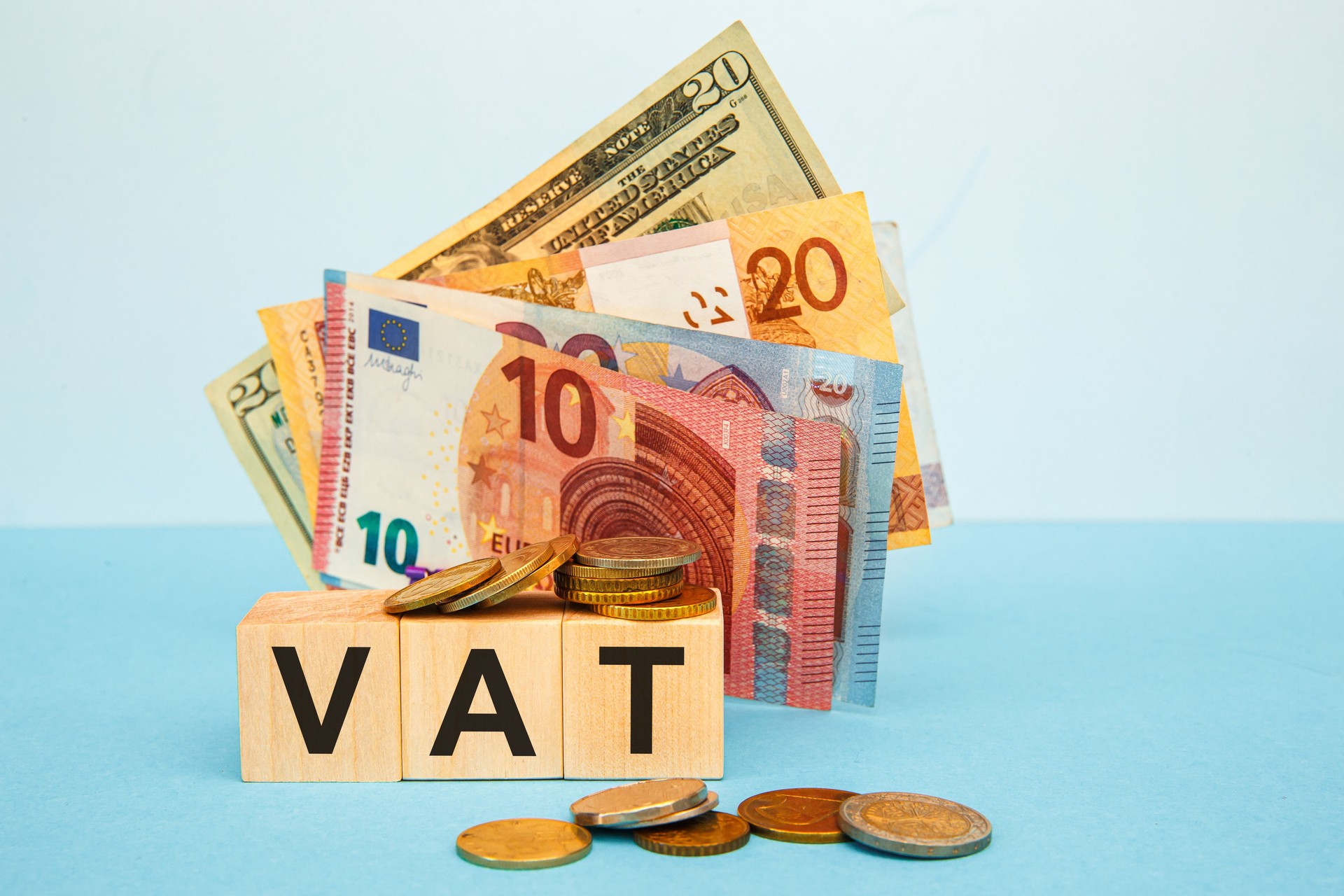 VAT word written on wood cubes on the background of various banknotes.